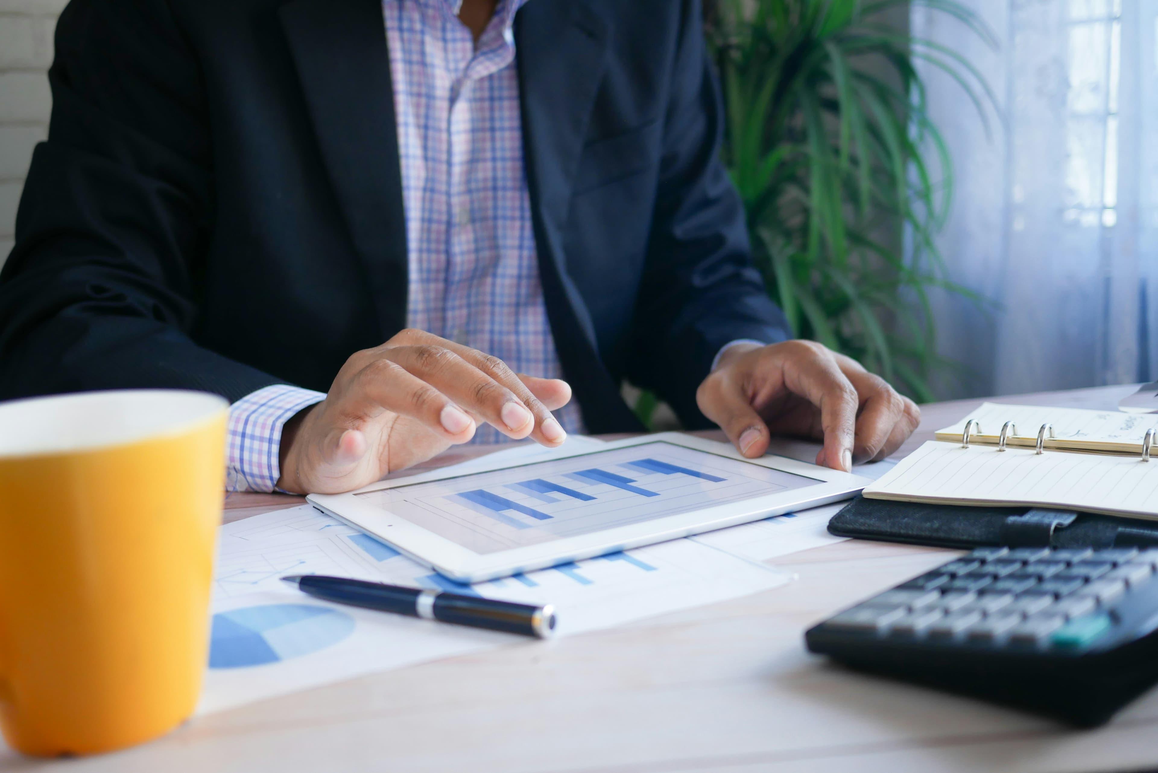 Business professional reviewing charts on a tablet alongside planning documents